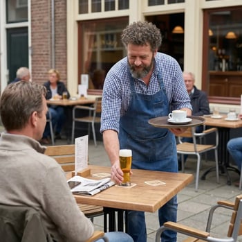 Caféhouder serveert een biertje en koffie aan gasten op het terras van een café