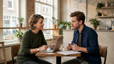 Horecaondernemer en medewerker bespreken een contract aan een tafel in een café