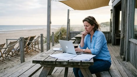 Eigenaresse van een strandpaviljoen werkt geconcentreerd op haar laptop op het terras